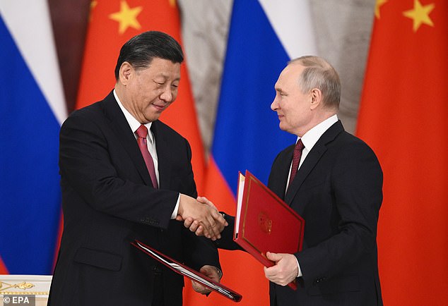 Speaking after talks with Chinese President Xi Jinping (pictured together), Putin said the move heralds the West switching to supplying Kyiv with weapons containing nuclear components, adding that Moscow will 'respond' if the UK goes ahead with its delivery of 14 next-generation battle tanks