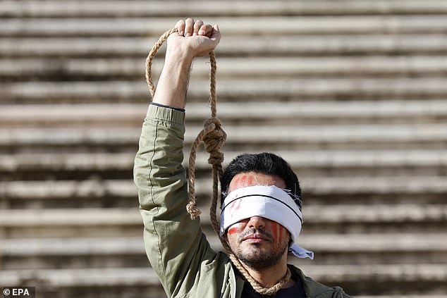 A demonstrator from the Iranian Portuguese community protests in front of the Parliament building in Portugal following Iran's sentencing to death and public execution of two young demonstrators, Mohsen Shekari and Majidreza Rahnavard