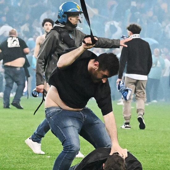 A Udinese fan attacks a Napoli fan with his belt in chaotic scenes at the Friuli stadium in Udine on Thursday night