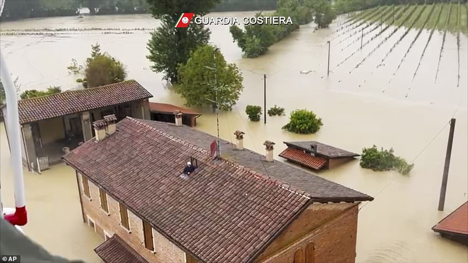 A man awaits rescue by helicopter on the roof of his flooded house in  the town of Faenza in the northern Italian region of Emilia Romagna today
