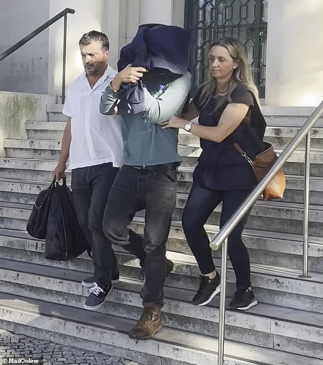 Josh James Menkens (centre) was pictured today being taken from a courthouse in the city of Leiria, an hour's drive away from the commune after being quizzed by a judge investigating the case