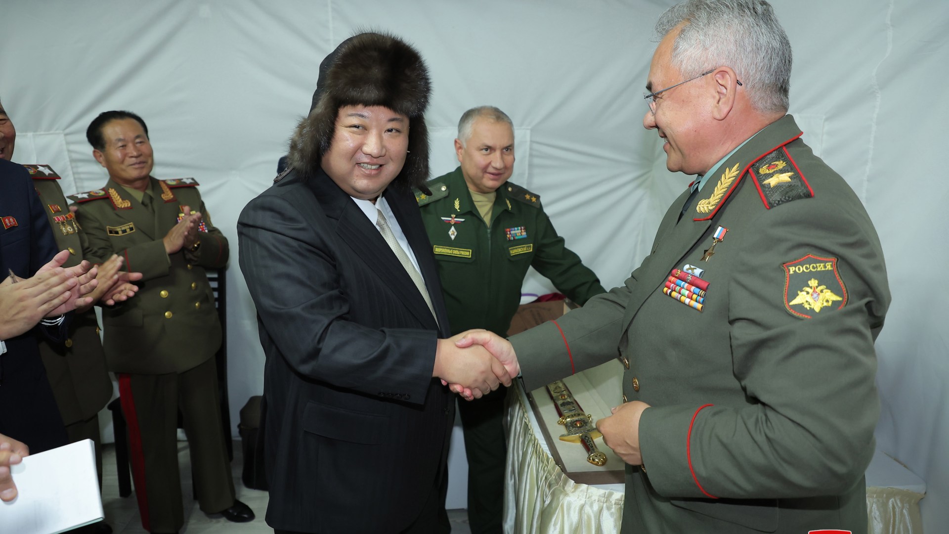Kim Jong Un wears a Russian fur hat as he shakes hands with warmonger Putin’s defence minister