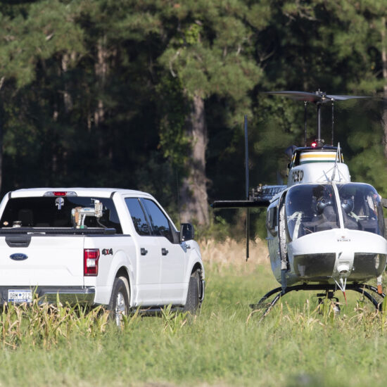 Pilots exit a Florence County Sheriff's Office helicopter after locating a missing fighter jet in a nearby field in Williamsburg County, S.C., on September 18. (Henry Taylor—The Post And Courier / AP)