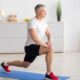 Older man at home lunging on a yoga mat
