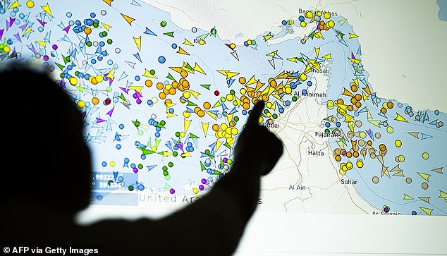 TOPSHOT - A photo illustration taken in Nicosia on May 4, 2026, shows a person in front of a large screen displaying vessel movements in the Strait of Hormuz on a ship-tracking website. Iran's navy fired 'warning shots' at US warships in the Strait of Hormuz on May 4, state media said, after the American military sent cruisers into the Gulf as part of a plan to help trapped commercial vessels leave. Earlier, US President Donald Trump had announced a plan to guide ships from neutral countries out of the Gulf, saying it was a humanitarian effort to help their stranded crews. (Photo by AFP via Getty Images)