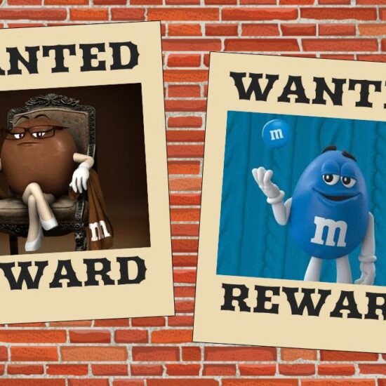 Two wanted signs hang on a brick wall, displaying photos of the brown and blue m&ms characters.