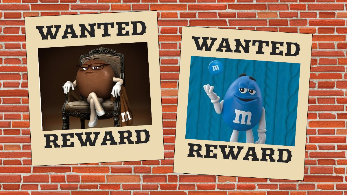 Two wanted signs hang on a brick wall, displaying photos of the brown and blue m&ms characters.