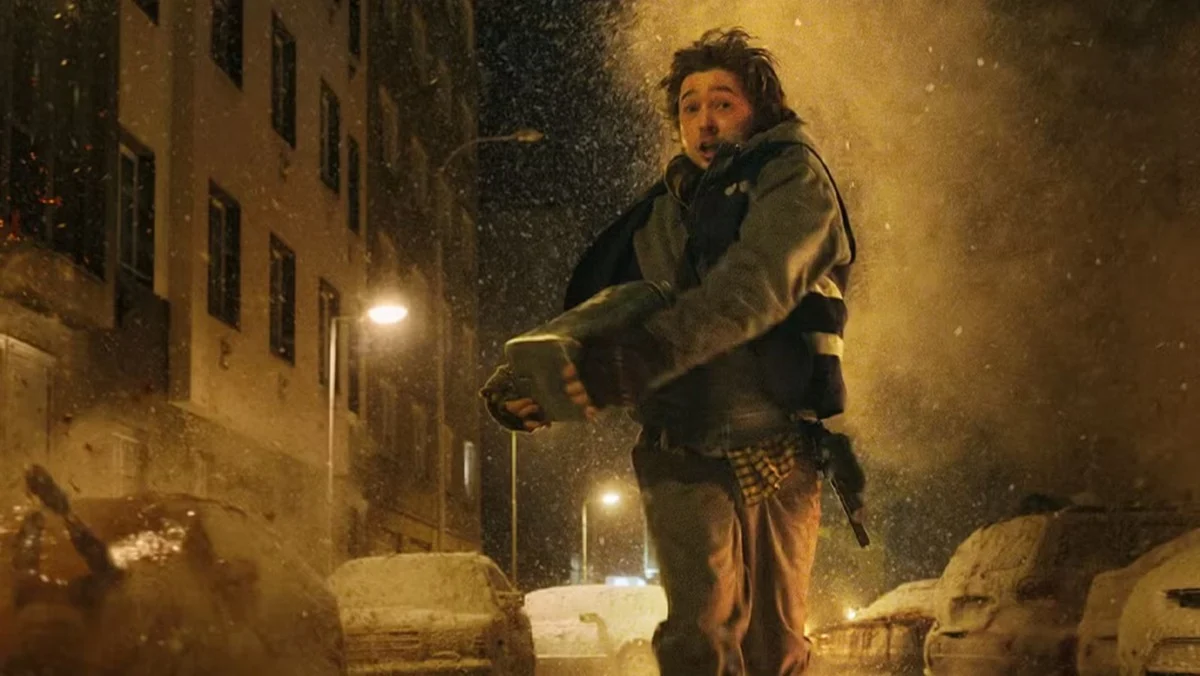 Bryan (Austin Abrams) runs from falling zombies in the streets of Raccoon City in Resident Evil.