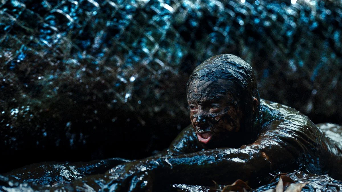 A still from Beware Boi&uacute;na, showing a terrified doctor covered in mud with the enormous snake behind her.