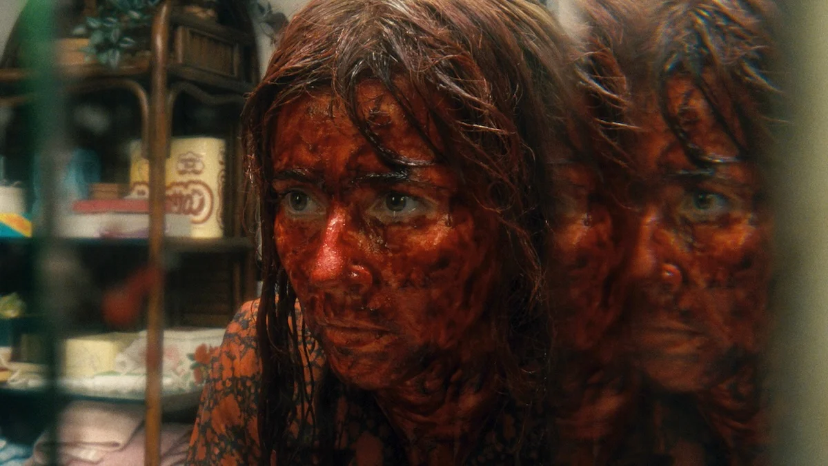 A blood-soaked Linda Cardellina seen with a double reflection on Crystal Lake