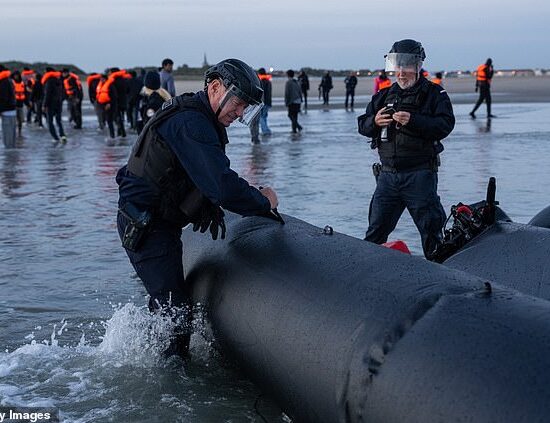 A French officer punctures an inflatable vessel with a knife after it was abandoned on a beach at Gravelines, northern France, following a failed crossing attempt