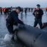 A French officer punctures an inflatable vessel with a knife after it was abandoned on a beach at Gravelines, northern France, following a failed crossing attempt