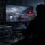 Anonymous gamer silhouette viewing blurred leaked gameplay beside equipment for an unnamed project