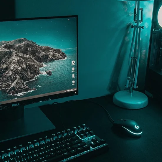 A high-end gaming PC setup with a monitor, mechanical keyboard, mouse, and a glowing desktop tower in teal lighting.
