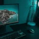 A high-end gaming PC setup with a monitor, mechanical keyboard, mouse, and a glowing desktop tower in teal lighting.