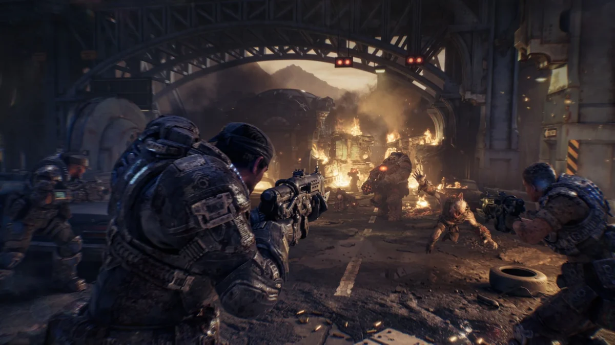 Soldiers in heavy armor fighting monsters in a ruined industrial setting from Gears of War: E-Day.