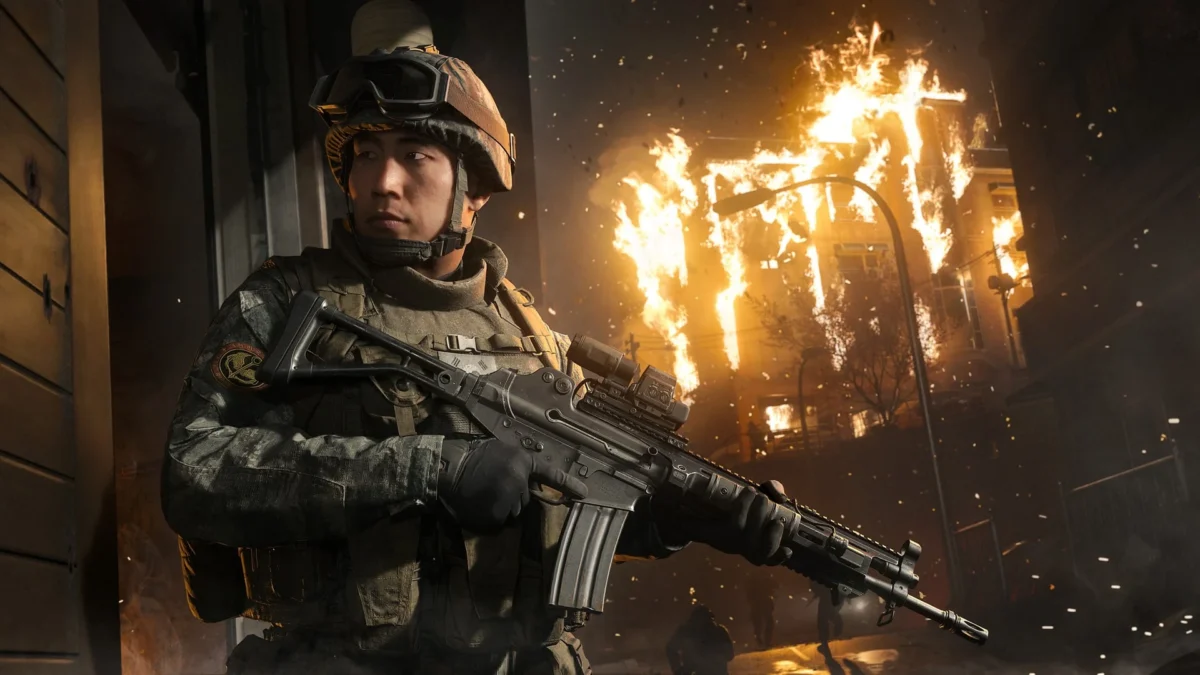 A soldier in tactical gear holding a rifle in front of a burning building in Call of Duty: Modern Warfare 4.