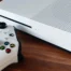 A white Xbox console and wireless controller on a wooden surface.