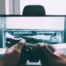 A person holding a video game controller in front of a television screen